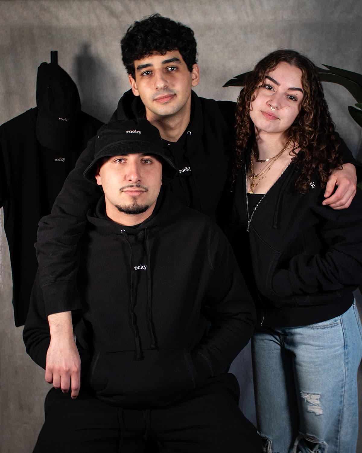 Three people in black Rocky merchandise with green plants